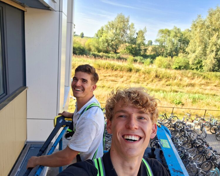 Quinten en Patrick Burm op een hoogwerker langs de gevel van een bedrijfspand