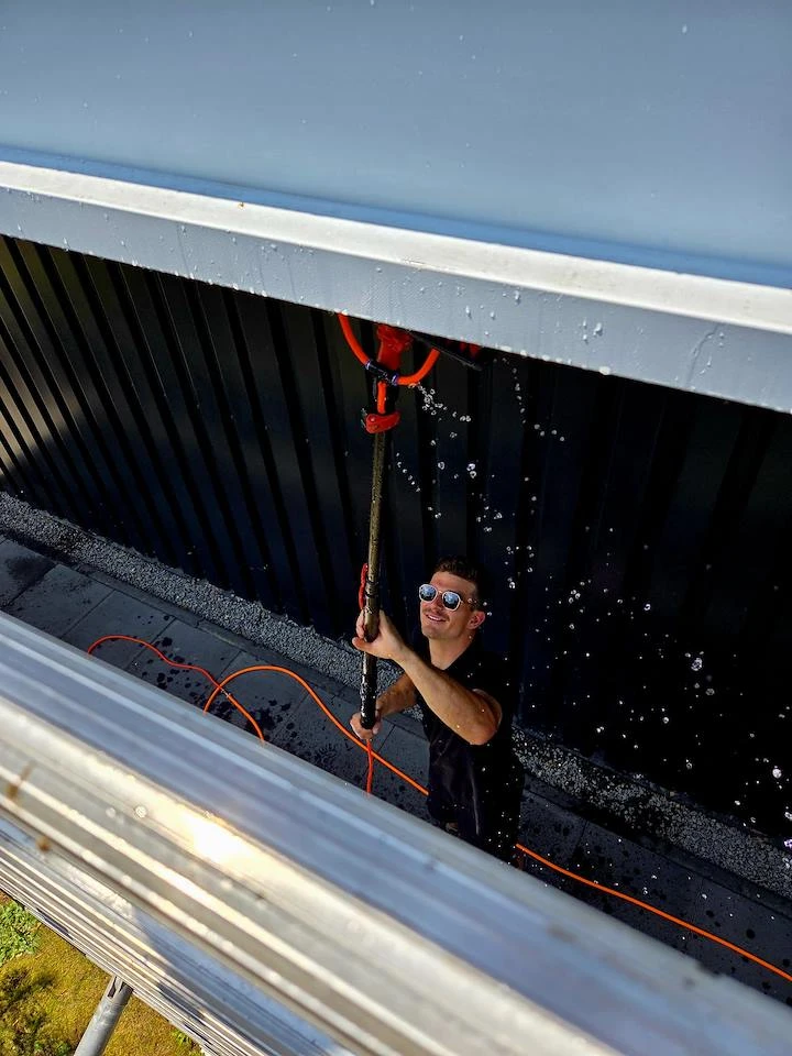 Patrick van Burm & Co reinigt boeidelen met een borstel op een telescoopsteel
