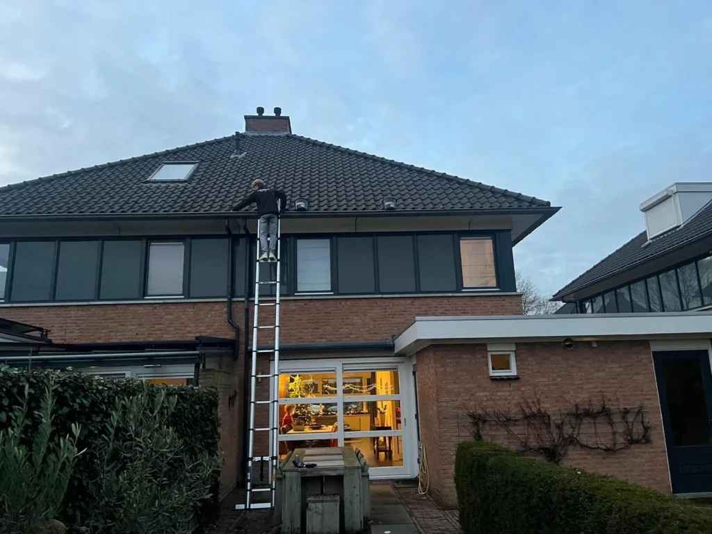 Quinten van Burm & Co op de ladder bij de dakgoot van een woning in Breda