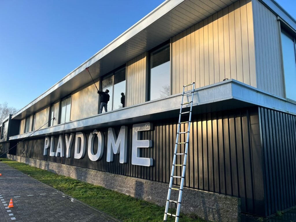 Gevelreiniging van beplating bij Playdome Roosendaal met een telescoopsteel door Burm & Co