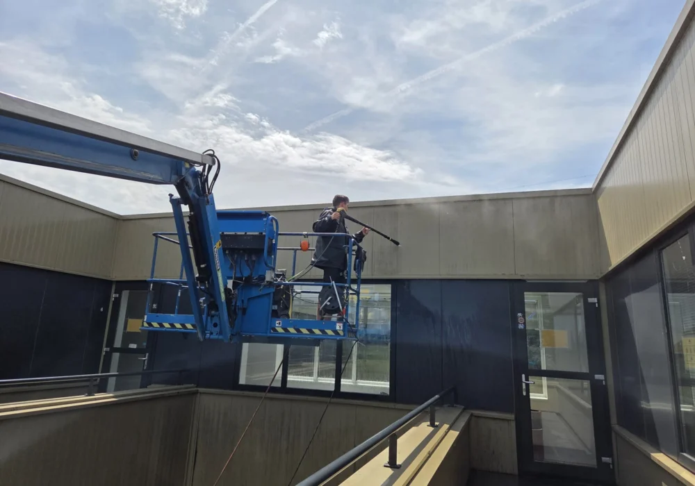 Gevelreiniging van een bedrijfspand vanuit een hoogwerker door Burm & Co