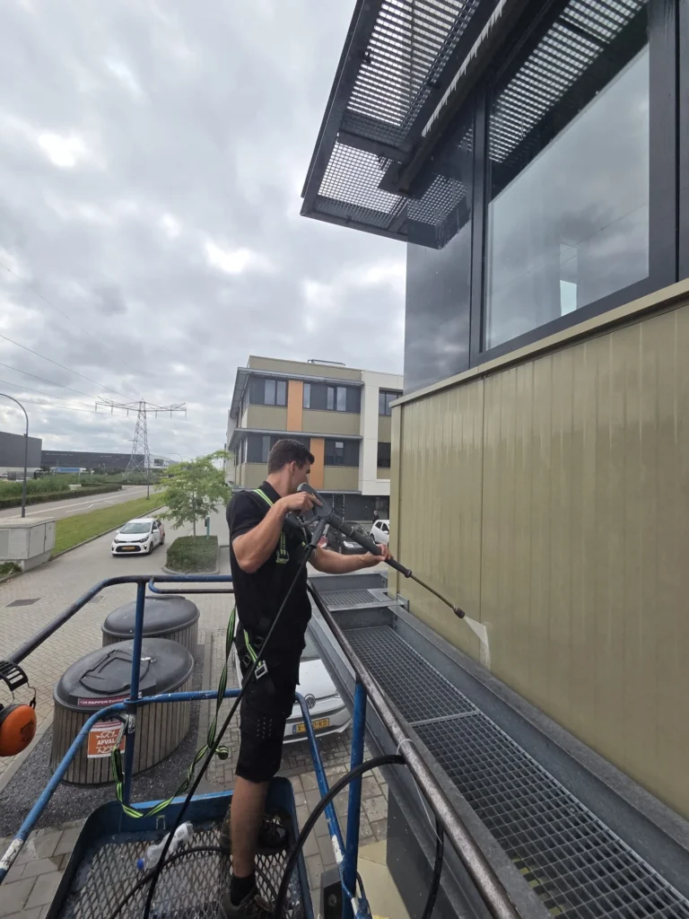 Quinten reinigt beplating met de lans vanuit een hoogwerker