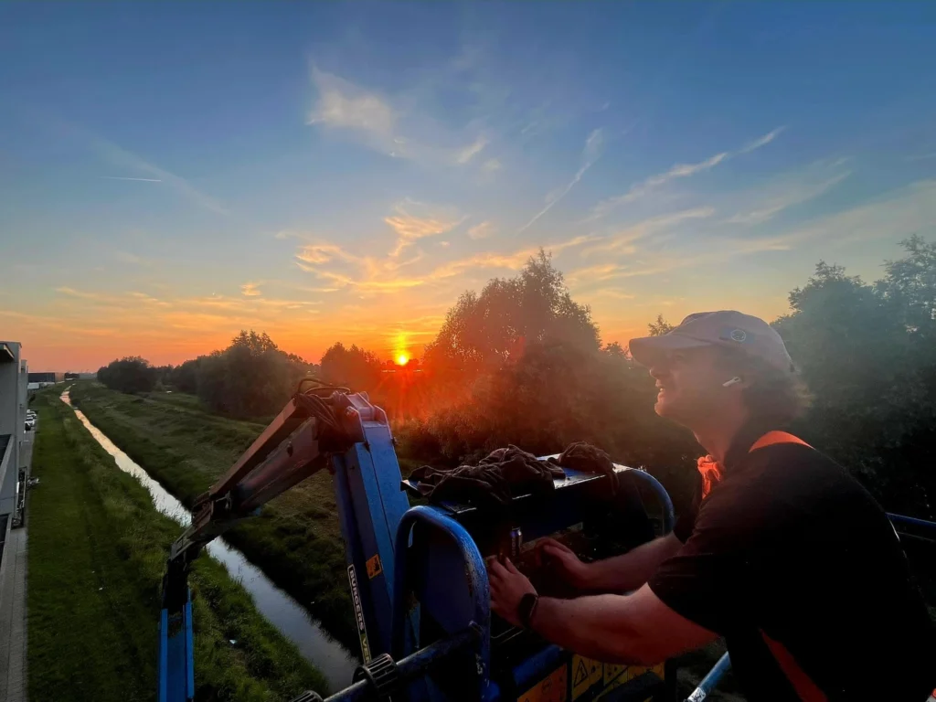 Burm & Co aan het werk in de hoogwerker bij zonsondergang