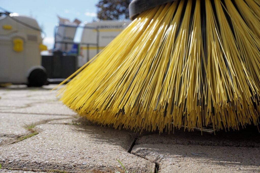 Veegborstel veegt zand in de voegen tussen betonklinkers