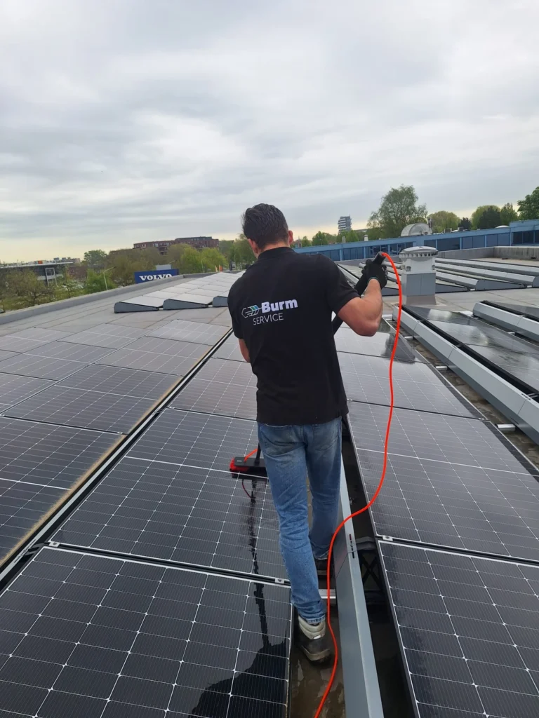 Zonnepanelen reinigen met de telescoopborstel op het dak van Bluekens Volvo door Burm & Co