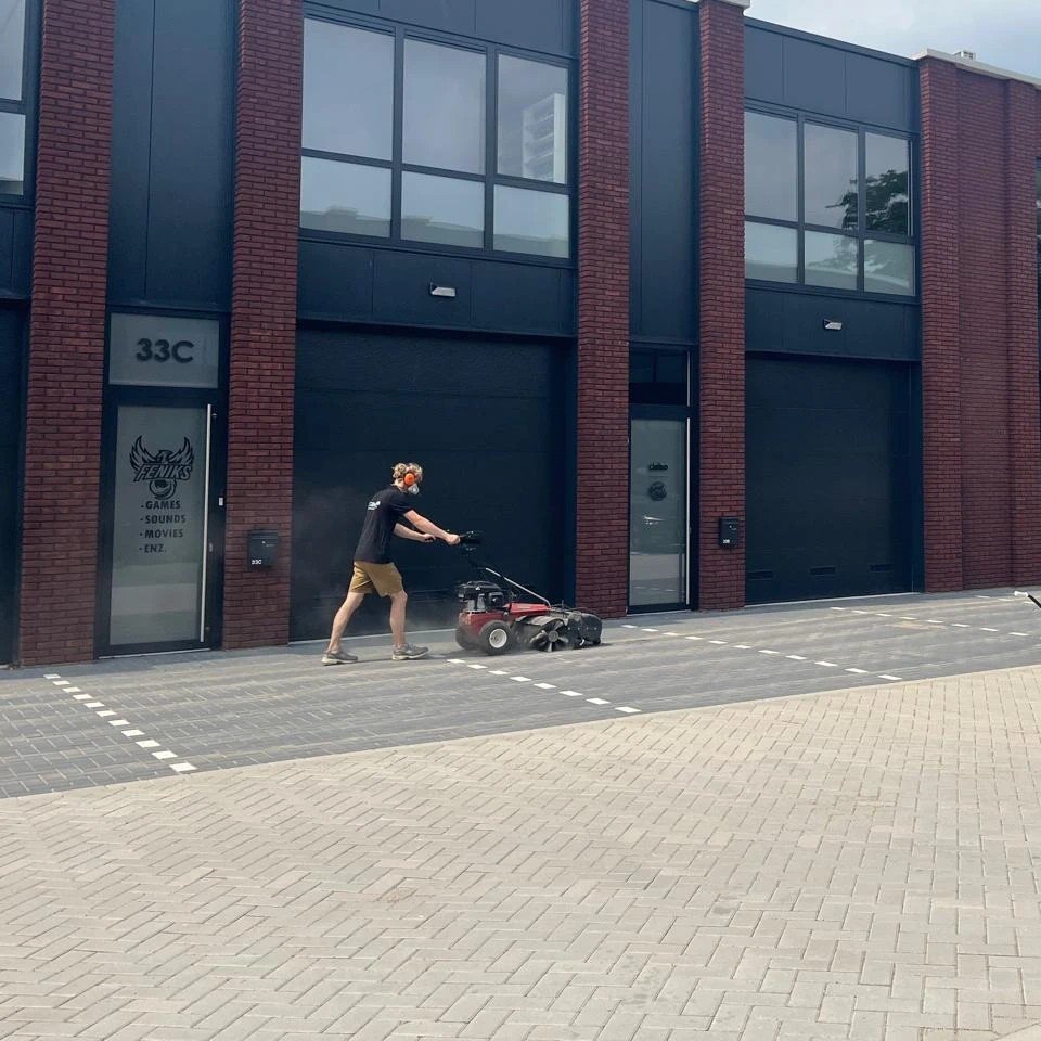 Parkeerplaats vegen met de veegmachine bij een bedrijfspand door Burm & Co
