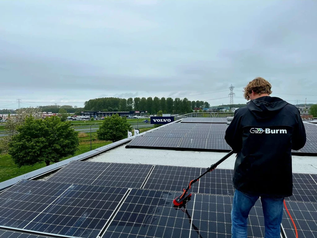 Zonnepanelen reinigen op het dak van een bedrijfspand met een telescoopborstel